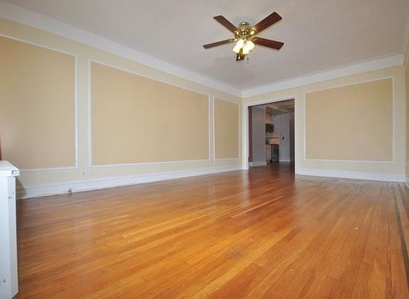 Large Sunny living room with a cove ceiling, wall and picture molding and refinished hardwood floors