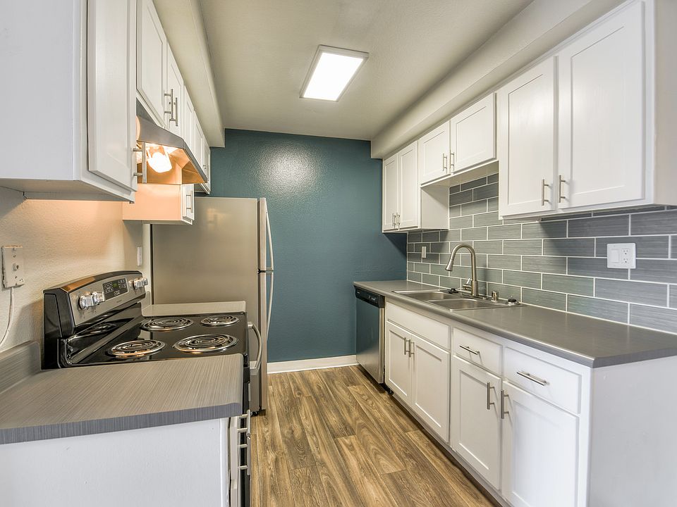 Kitchen with stainless steel appliances, gray counter tops and white cabinets.