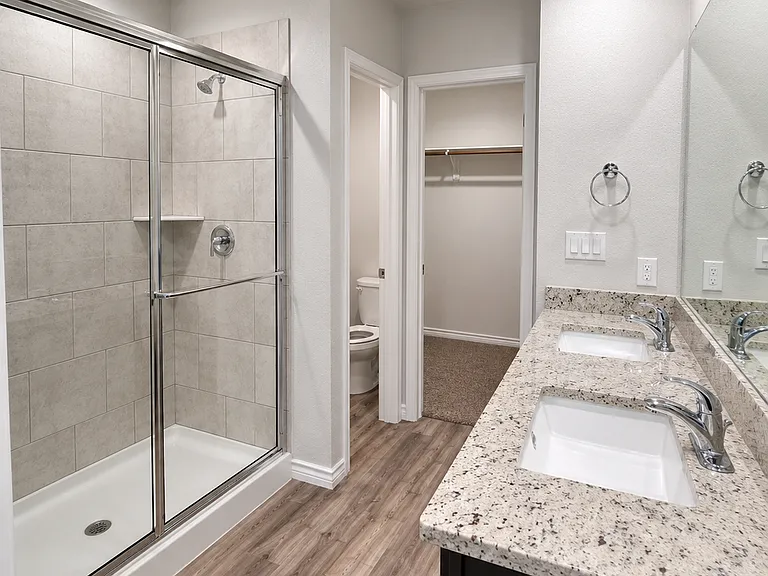 Primary bath with double vanity, shower, and closet access