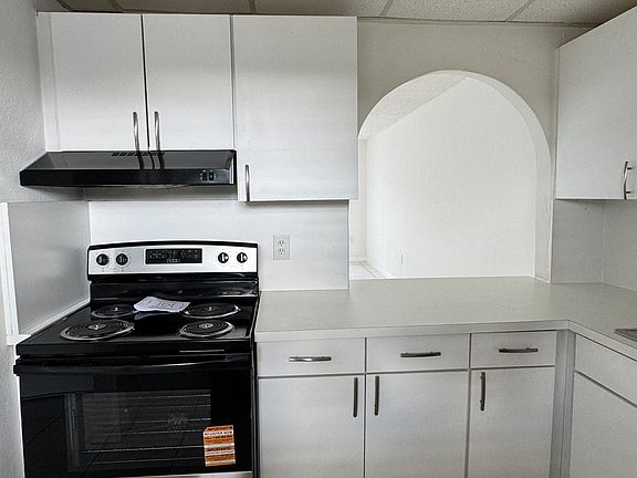 Full kitchen with all new appliances and countertops. An arch overlooking the living room with seating.