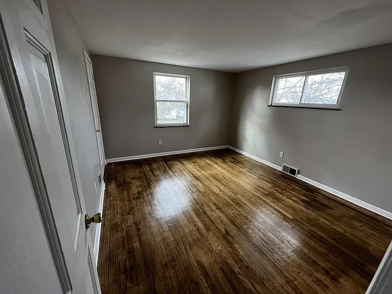 Front bedroom with walk-in closet and refinished hardwood floors