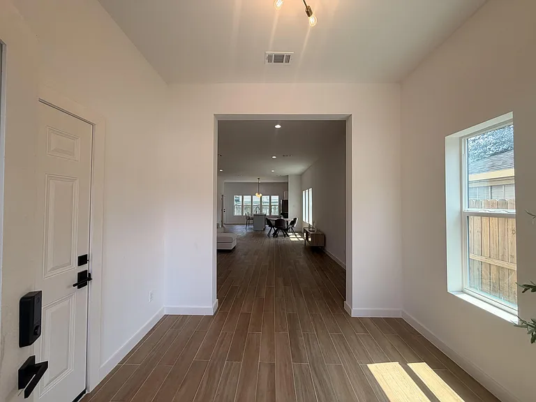 Entry hallway with tile flooring and high ceilings opens to the main living area, with a large window for natural light.