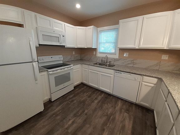 Kitchen with granite countertops, tile backsplash, plentiful cabinet space, dishwasher, and new appliances.