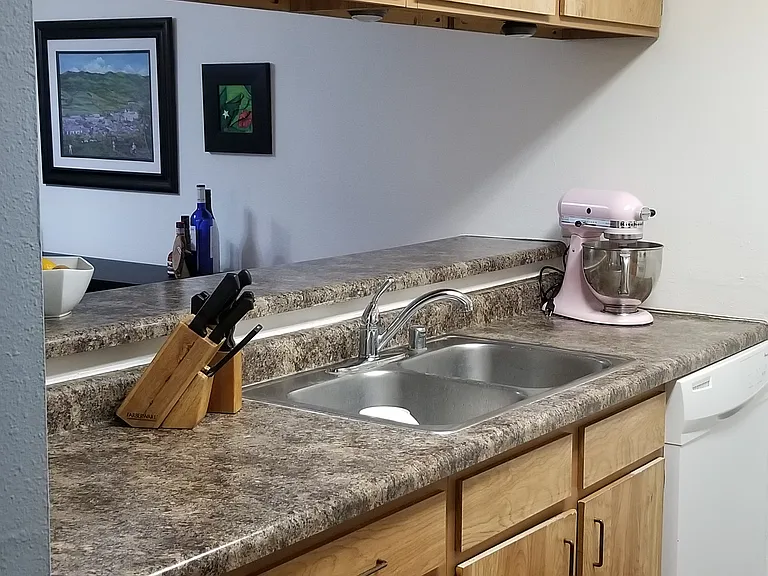 Other side of kitchen with pass-through to the dining area. Sink and dishwasher can be seen.