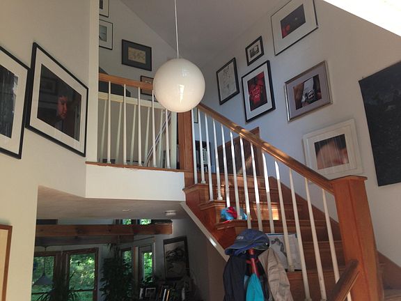 Inside front door, stairs to the sleeping loft and full bathroom. All original art, photographs, paintings and drawings. Straingt ahead are dining area windows and on right, door to back deck.