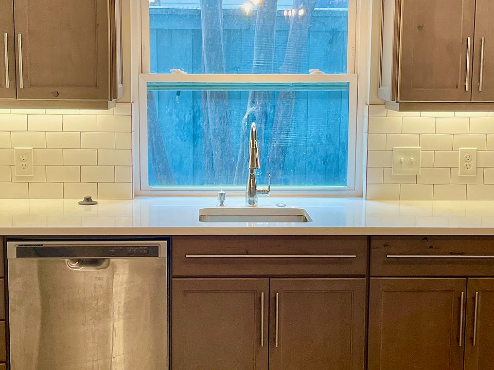 Updated kitchen with medium-dark cabinetry, white subway tile back splash and designer lighting.