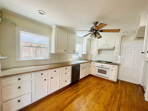 Spacious kitchen with gas burners, dishwasher, fridge, and many cabinets for storage