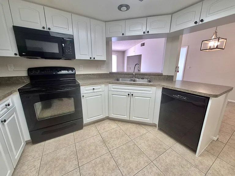 Kitchen with stove, microwave, dishwasher and unobstructed view of lounge & dining area.