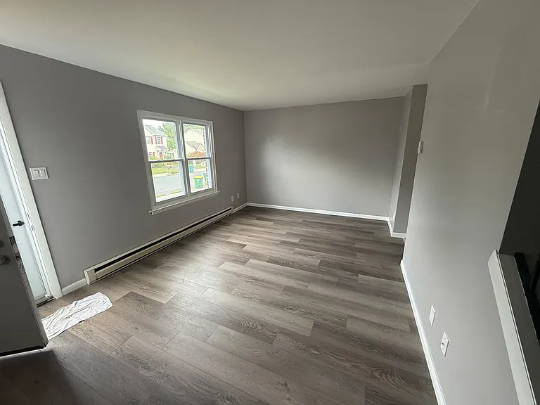 Spacious living room with newly placed flooring and freshly painted walls for the modern home look