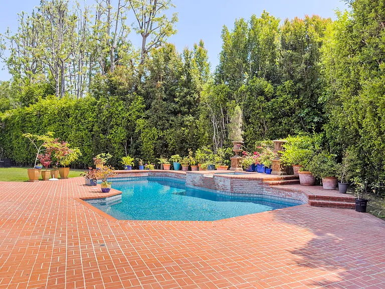 Statue fountain accent and towering trees add resort charm to this pool at this Beverly Hills luxury rental, 1094 Garden Lane, 90210.