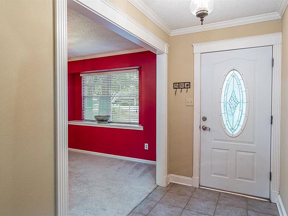 Open the door to the tiled entryway, accented with crown moulding. To the right is the formal dining room with large window and wide sill for displaying a decorative item.