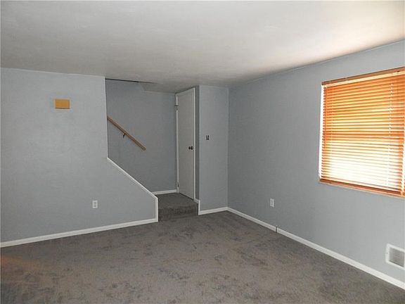 ANOTHER VIEW OF THE LIVING ROOM WITH A COAT CLOSET AND STAIRS TO THE BEDROOMS.