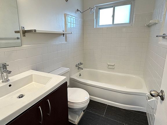 Subway tile bath surround, black tile flooring, farmer's sink, nickel hardware, rainfall showerhead and a window, too.