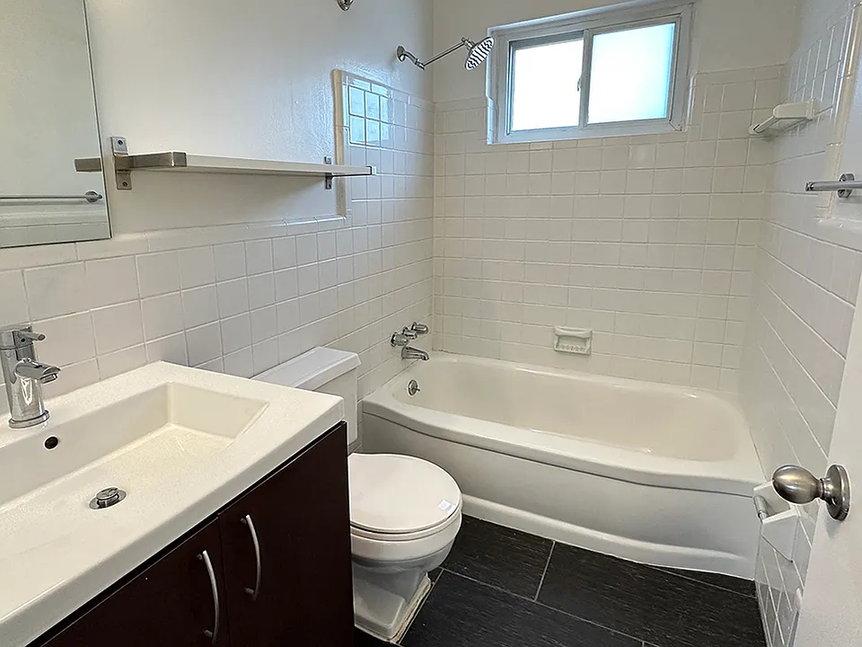 Subway tile bath surround, black tile flooring, farmer's sink, nickel hardware, rainfall showerhead and a window, too.
