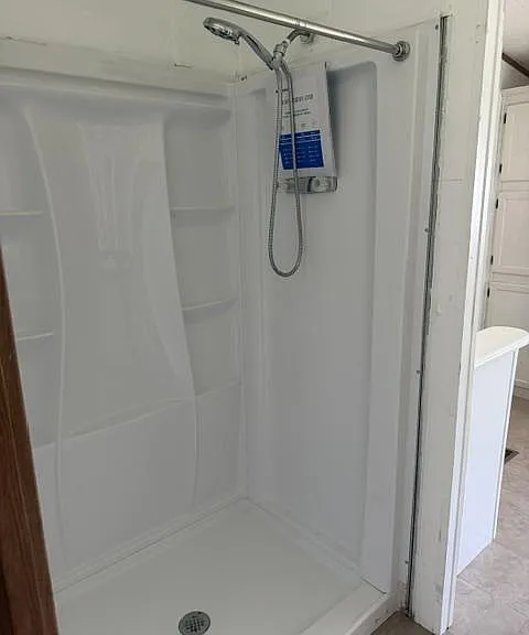 Clean walk-in shower stall with built-in shelving and a mounted showerhead for convenient daily use.