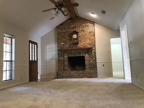 Large living room has lots of space, a brick fireplace, ceiling fan and lots of natural light.