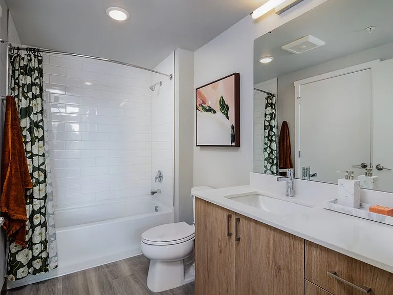 Primary bathroom with oak cabinetry, white granite countertops and white tile