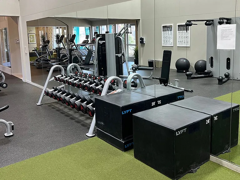 Spacious, modern gym with diverse fitness equipment and mirrored walls creating an energizing workout environment.