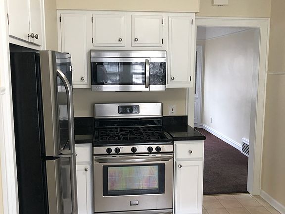 Stainless steel gas stove, refrigerator, and microwave.