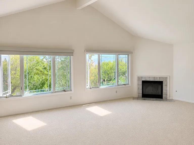 Spacious primary bedroom with fireplace, large windows, and beautiful scenic views