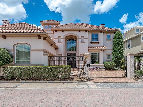 MAIN HOUSE FRONT ELEVATION WITH STRIKING MEDITERRANEAN FEATURES, GATED DRIVE AND PAVERED DRIVEWAY.