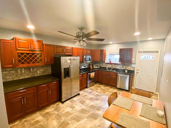 Spacious tiled Kitchen with granite counters, integrated wine rack, and stone backsplash.