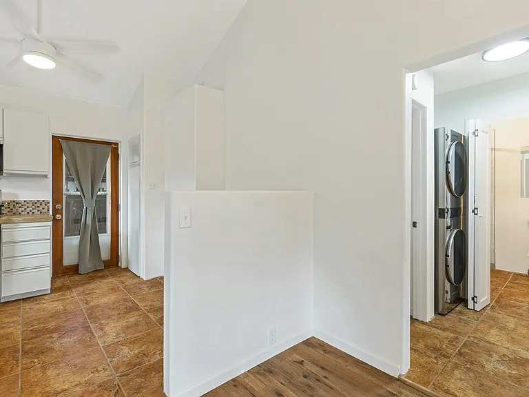 Showing new washer dryer to the right and to the left of the half wall is a banco perfect for a dine-in spot.
