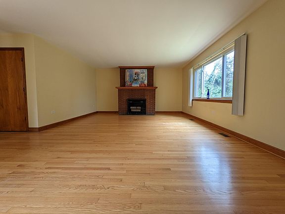 Oak floors & fireplace in living room overlooking yard.