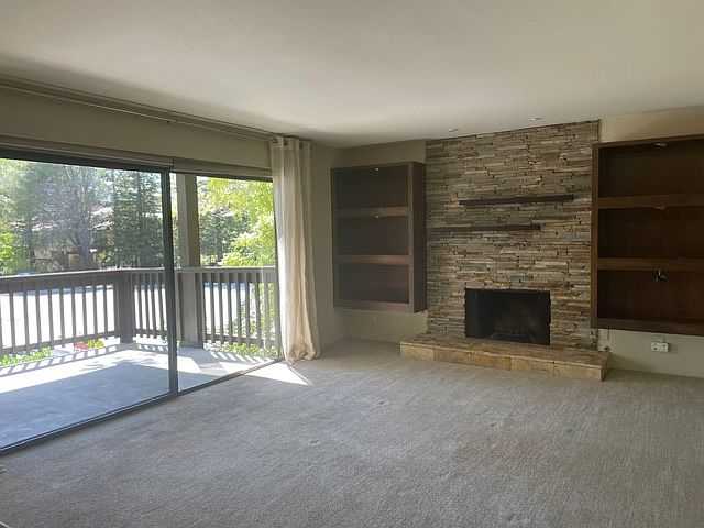 Living room. Stone fireplace, custom built-in lighted book shelves, custom window treatments.