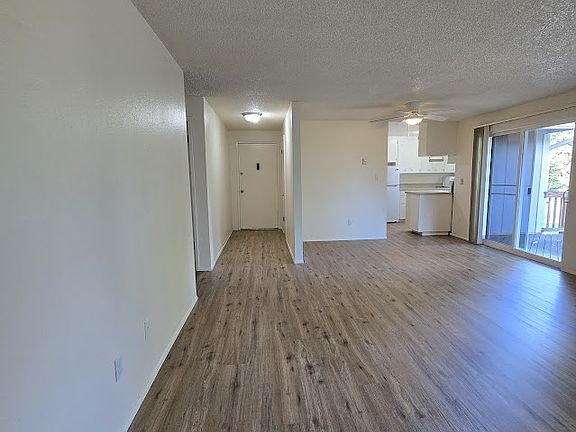 This is taken from the far end of the Livingroom /Dining area. It also shows a long entryway hall with a coat closet. It also shows the entry to the kitchen along with the sliding glass door to the deck.