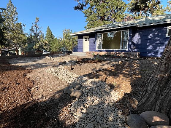 Landscaping in front yard includes river rock, bark and new plants