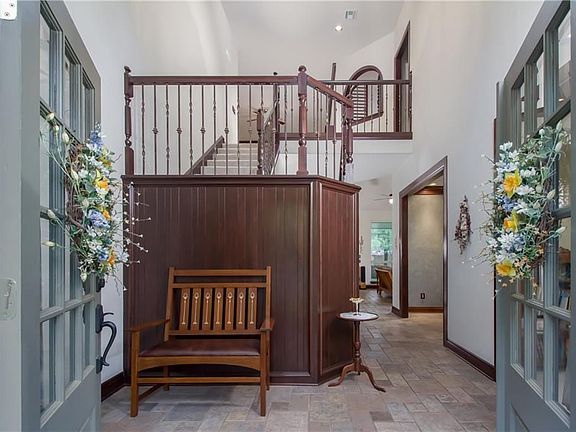 Entry ceiling soars to the second floor where the plantation shuttered window looks onto the family livingroom below.  Iron ballasts adorn the beautifully crafted stairs while comfortable spaces allow easy traffic flow.