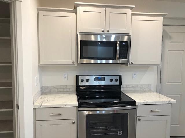 Stainless steel stove and microwave, ample cupboard space.