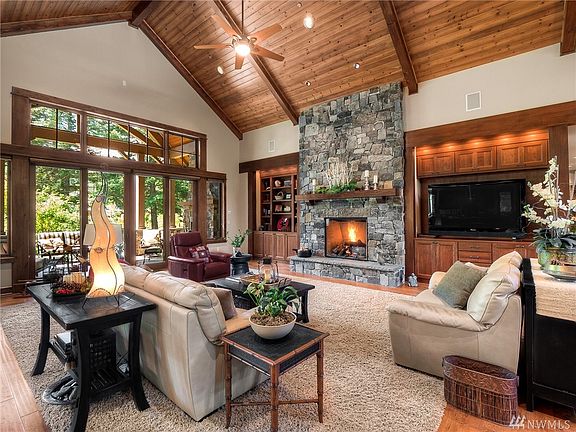 A floor to ceiling stone fireplace framed by built-in cherry cabinetry and bookshelves is the focal point of the great room. Full light double doors open to the extensive outdoor living area for entertaining.  Speakers provide music throughout most of the home and the patio.