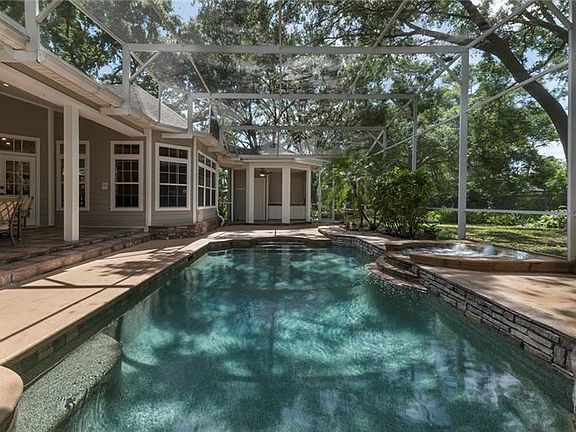 Spa and pool feature stack stone waterfall; outdoor kitchen with Jennaire grill and detached pool bath beyond