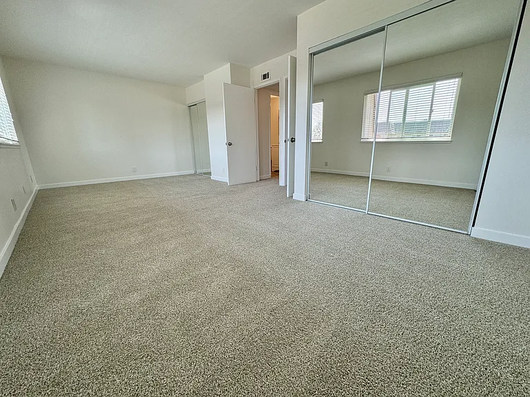 Spacious master bedroom (2 bedrooms converted to 1) with new wall to wall carpet, mirrored wardrobe doors and paint!