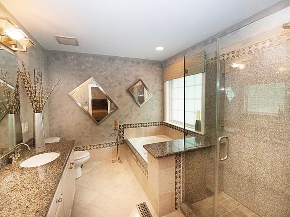 master bathroom with heated floors, garden tub, granite shower and double granite countertops