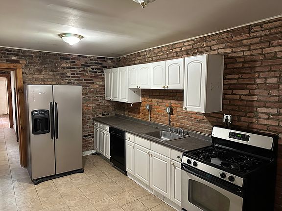 Kitchen with steel, gas oven, and exposed brick