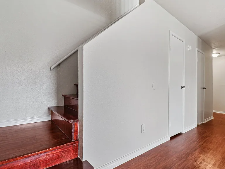 Modern hallway with wood-style flooring and elegant stairs leading to an inviting upper level. Modern hallway with wood-style flooring and elegant stairs leading to an inviting upper level.