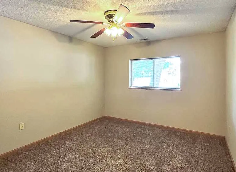This cozy bedroom offers soft carpet, a ceiling fan, and room for your full furniture set.