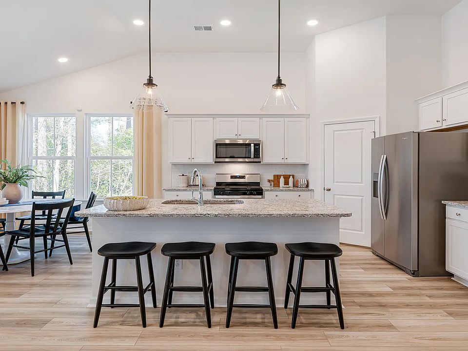 Open kitchen Avondale model in Bluffs at Sun Colony in by DRB homes offering light wood floors and h