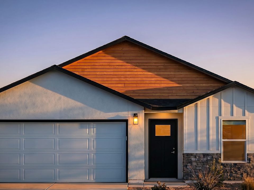 Modern single-story house at sunset with a two-car garage, dark front door, illuminated entry lights