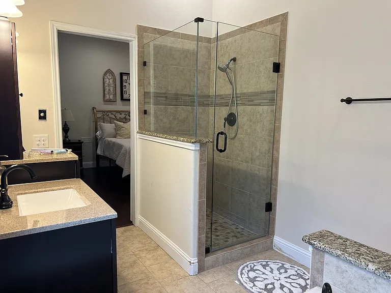 Elegant walk-in shower with custom tile surround, frameless glass enclosure, and modern fixtures.