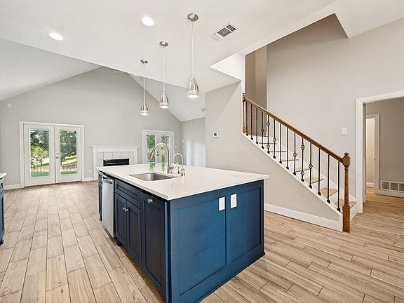 Central island featuring a stainless steel sink with a gooseneck faucet, integrated dishwasher, and pendant lighting