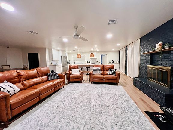 Living room with leather reclining sofas, wood-burning fireplace, & large TV.