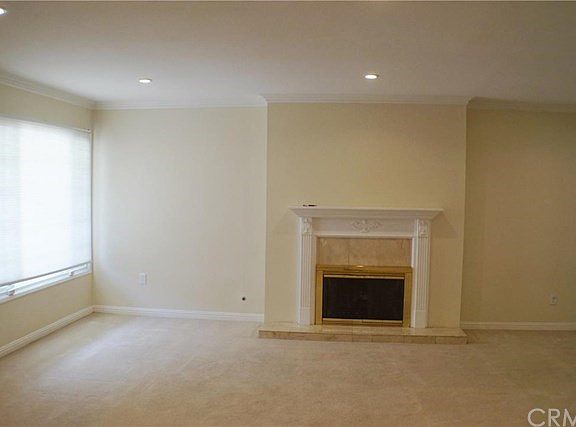 LIVING ROOM- Marble tiled fireplace with decorated wood mantel piece, recessed lighting, and crown moldings.