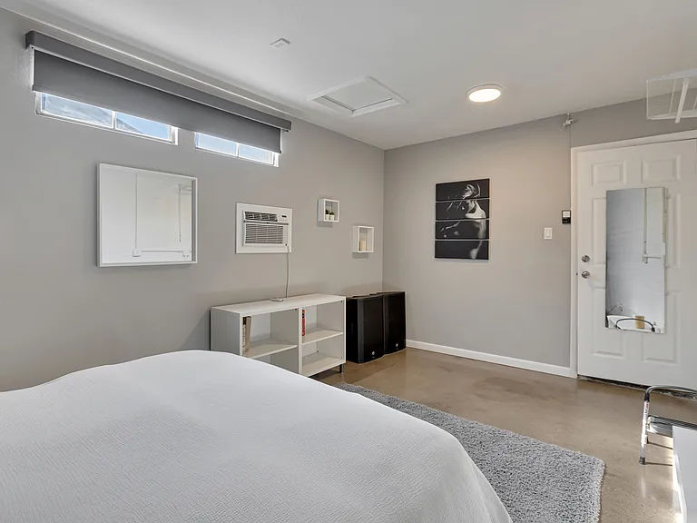 Guest bedroom featuring a dedicated AC unit and blackout shade