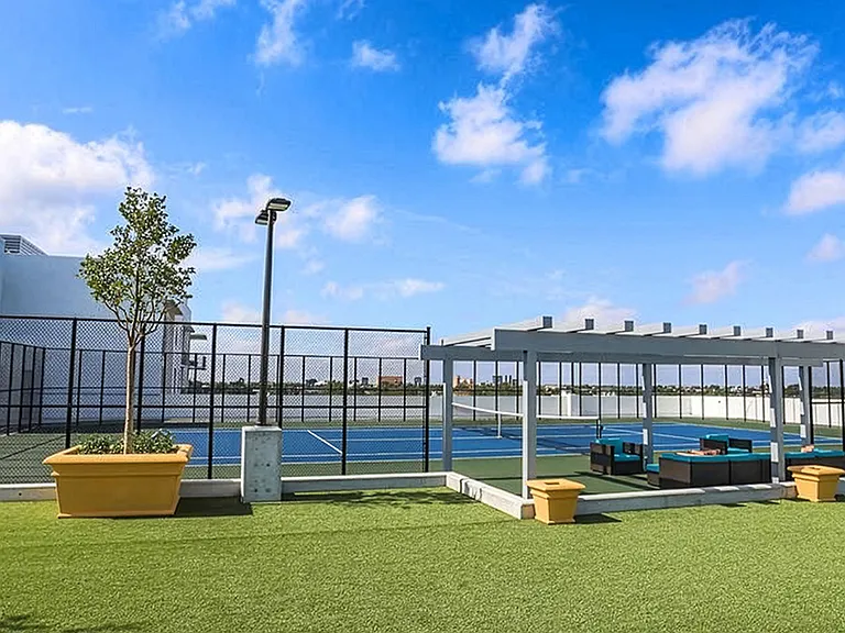 Luxury apartment community tennis court with professional playing surface and open skyline views