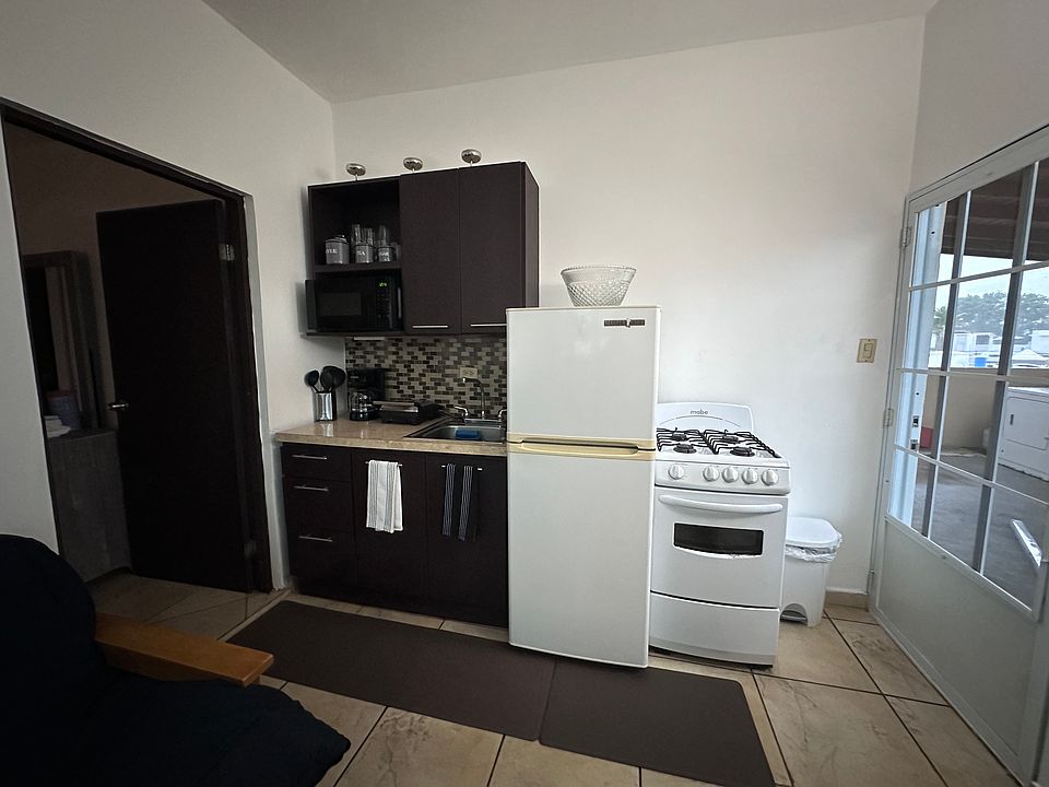 Small kitchen with all the necessary equipment: Stove, Coffee Maker, Panini Press, and fridge.