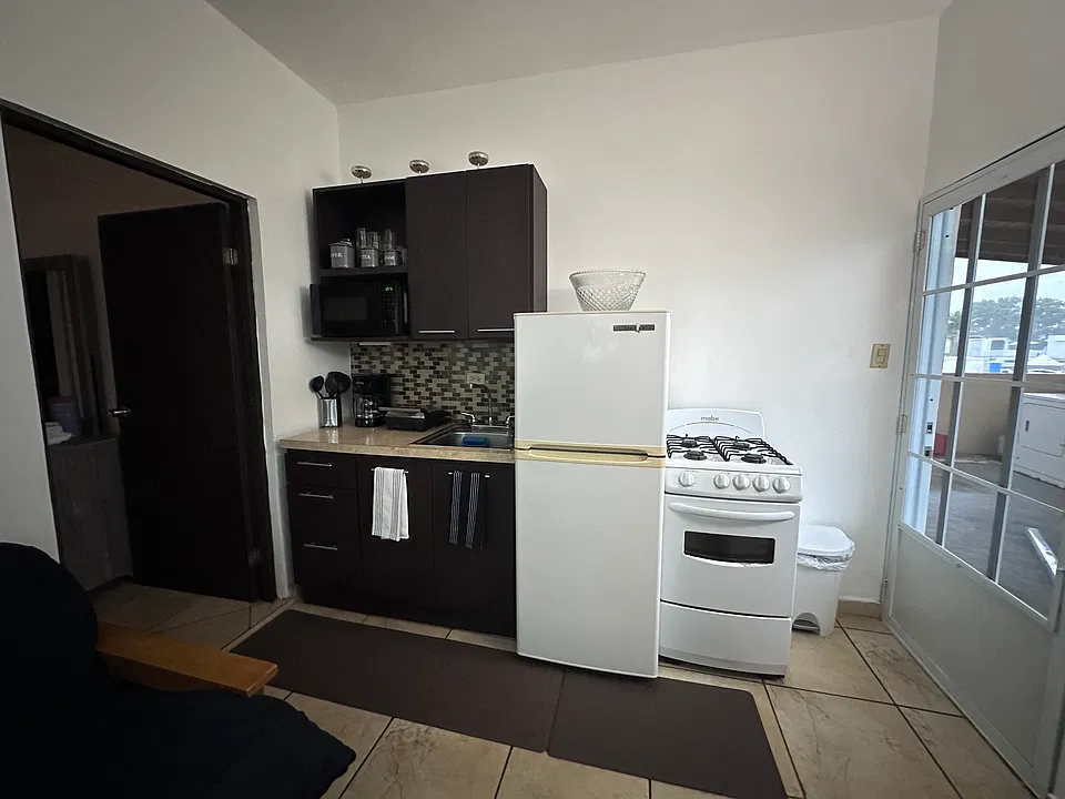 Small kitchen with all the necessary equipment: Stove, Coffee Maker, Panini Press, and fridge.